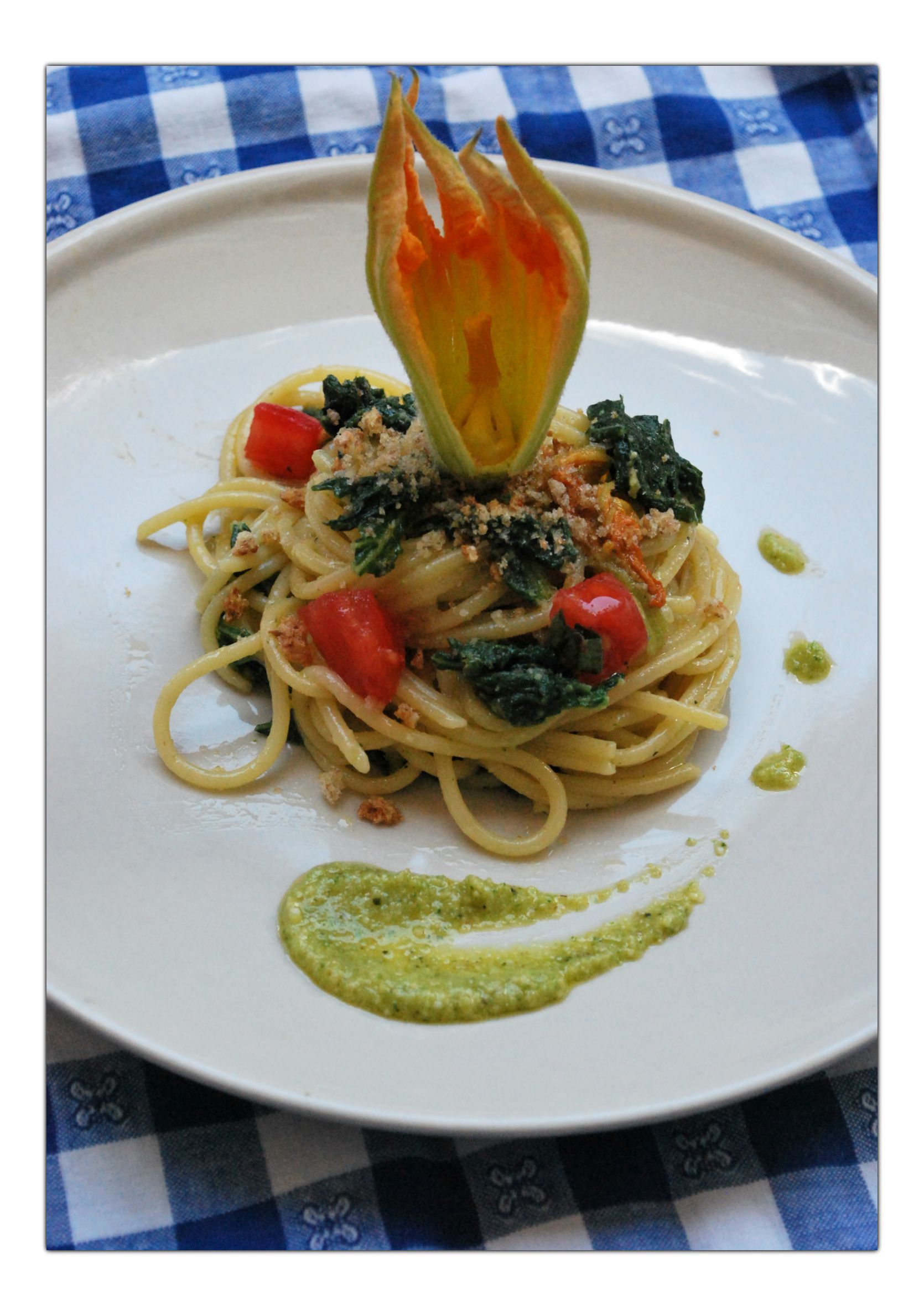 Spaghetti con fiori, foglie e pesto di zucchine, dadini di pomodori e pangrattato piccante
